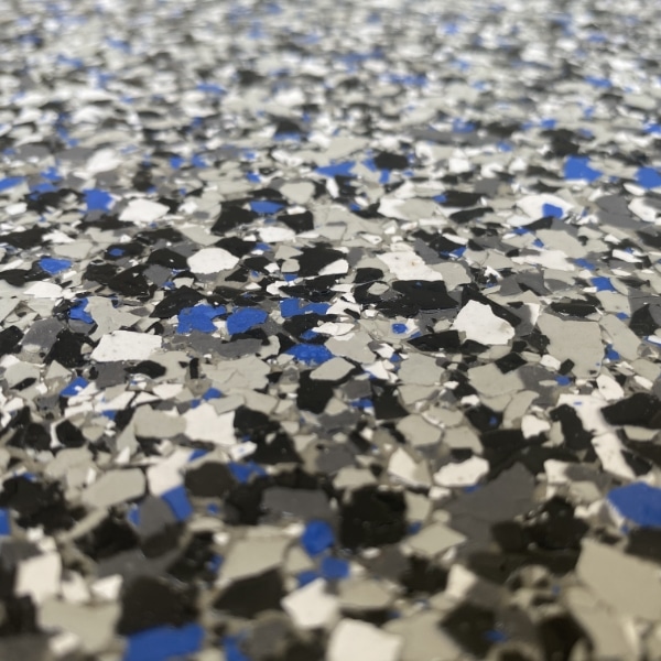 The image shows a speckled surface with a mix of black, white, and blue flakes, creating a textured and possibly slip-resistant flooring or material.