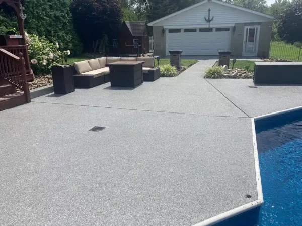 A backyard with a swimming pool, decorative concrete patio, outdoor furniture set, a wooden deck, and a detached garage with nautical decor.